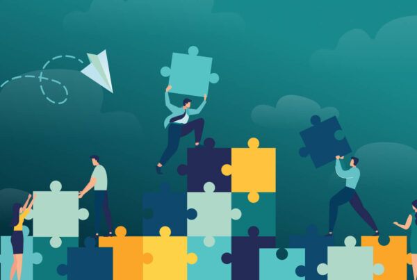 Six people collaborate to assemble and balance large puzzle pieces against a dark teal background with clouds.