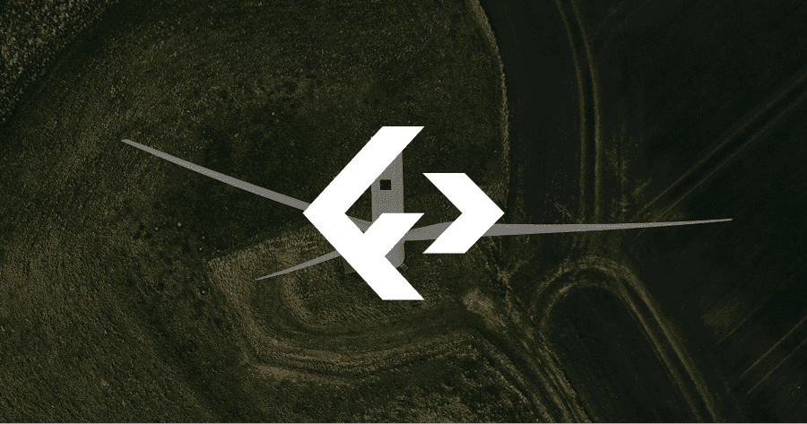 A drone captures an aerial view of a wind turbine with a large white logo overlay in the center, surrounded by green fields